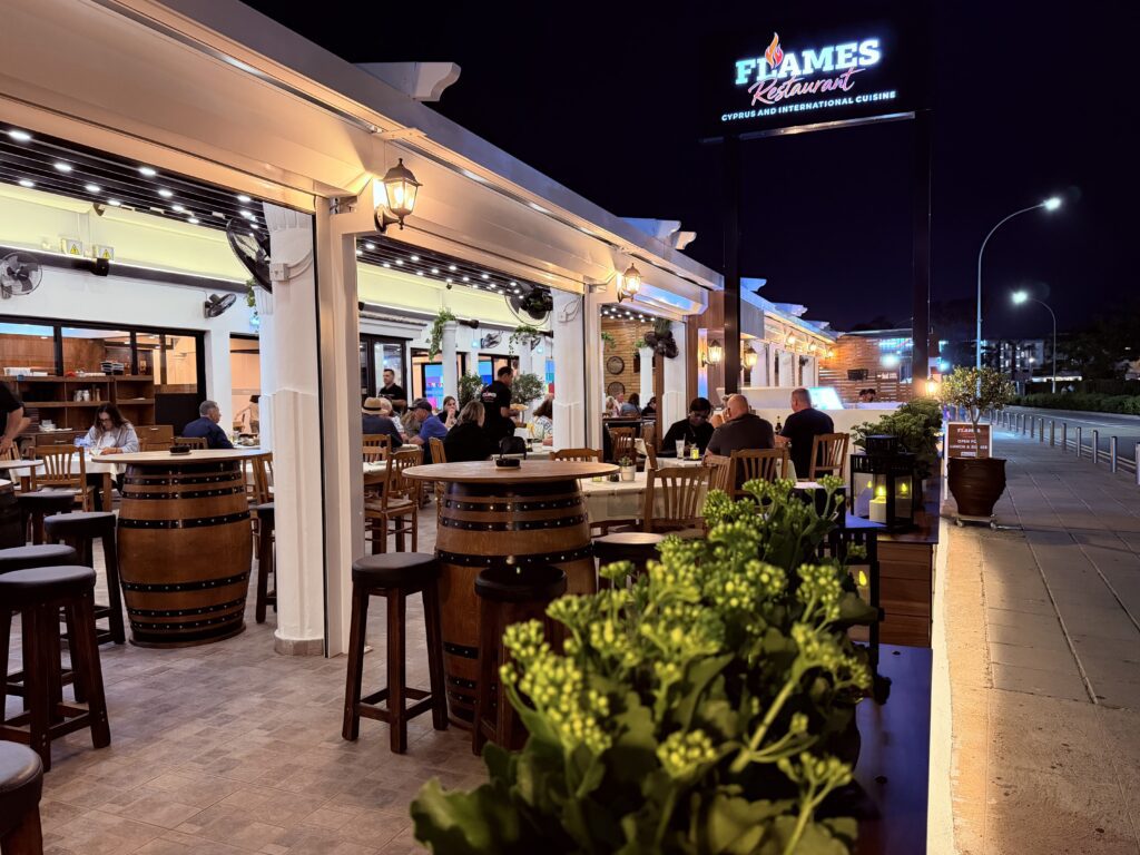 The covered terrace at night, barrel tables under string lights